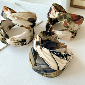 Three twisted bohemian print headbands in olive green and beige on a white surface