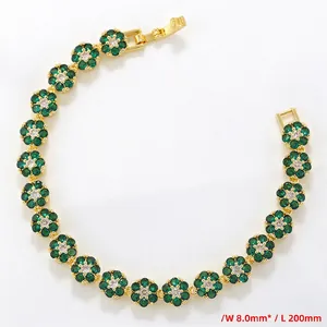 Close-up of golden flower tennis bracelet with green gemstones and clear center stones