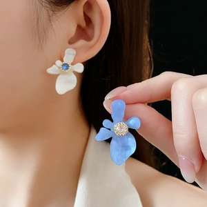 Vue détaillée des boucles d'oreilles fleurs en résine blanche et bleue avec cristaux