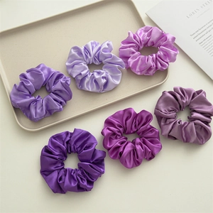 Detailed view of six purple gradient satin scrunchies arranged on a minimalist tray