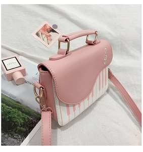 Detail view of the piano key pattern and treble clef embroidery on the pink fashion bag