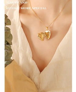 Gros plan d'un collier médaillon cœur doré porté sur un chemisier blanc vintage