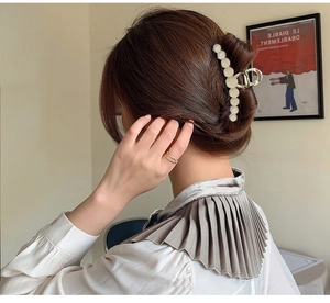 Detail of a large gold alloy hair claw with white opal beads on a woman's bun
