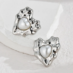 Irregular textured silver heart earrings with white faux pearl inlay on white rock