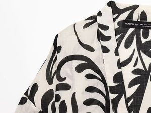 Detailed close-up of collar area on black and white leaf print linen kimono set with labels