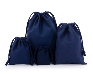 Detailed view of four dark blue drawstring cotton bags in varying sizes on white backdrop
