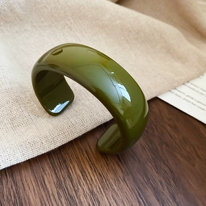 Gros plan d'un bracelet ouvert large en acrylique vert olive avec finition polie