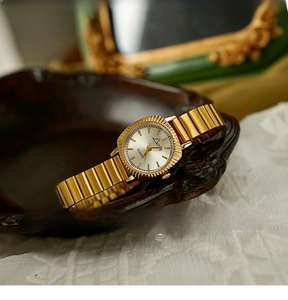 Detailed close-up of retro gold women's quartz watch with coin-edge bezel and elastic band