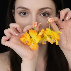 Detail of drop raffia earrings with beige rose top and orange floral petals