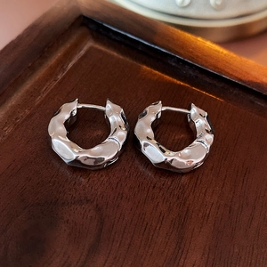 Macro shot of silver textured hoop earrings with irregular wrinkled metallic finish