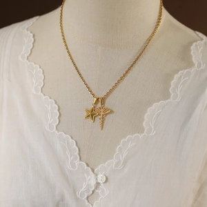 Detailed view of vintage gold plated Caduceus and star pendants on a dainty chain necklace