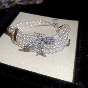 Détail macro du bracelet perles multicouches avec pendentif oiseau serti de cristaux