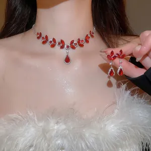 Elegant silver necklace and earring set with red teardrop crystals worn by a model