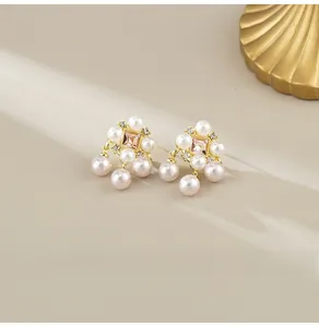 Detail of luxury pearl earrings with square pink gemstone and gold setting on silk