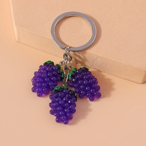 Macro shot of realistic purple resin grape charms with green leaves on a silver keychain