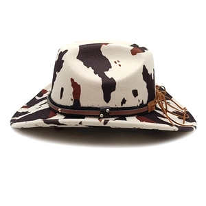 Detail of cow print cowboy hat featuring leather band with metal rivets and drawstring