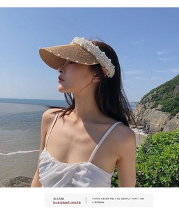 Close-up detail of woven straw sun hat visor with elegant pearl trim and beach background