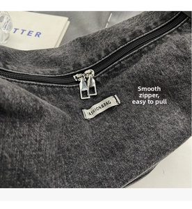 Detail of washed denim shoulder bag with smooth silver zipper and fashion label