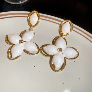 Détail de boucles d'oreilles fleurs dorées vintage avec incrustation nacrée sur assiette