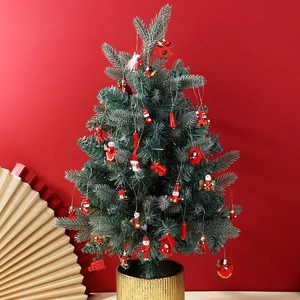 Mini green Christmas tree with wooden nutcracker and ornaments on red background