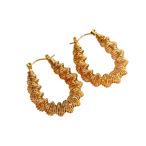 Detailed macro shot of 18k gold plated stainless steel wave spiral hoop earrings