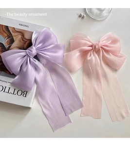 Detail of cream tulle bow hair clip with ribbons shown next to vintage books