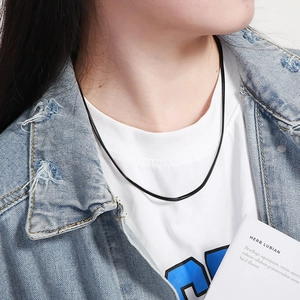Detailed view of a sleek black flat snake chain necklace worn with a denim jacket