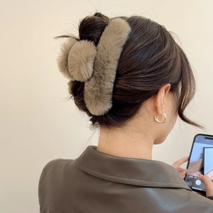 Close-up of a plush coffee brown faux fur shark hair claw clip worn on a woman's dark hair