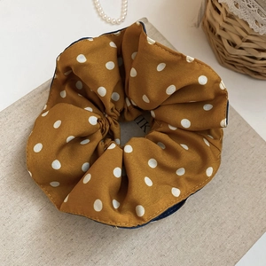 Detailed texture of brown polka dot scrunchie placed on a book with pearls