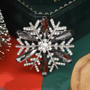 Macro shot of silver snowflake brooch with grey gems on a festive Christmas background