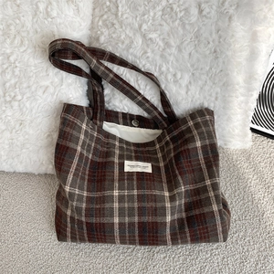 Detail of red-brown plaid tote bag featuring a secure magnetic closure and inner lining