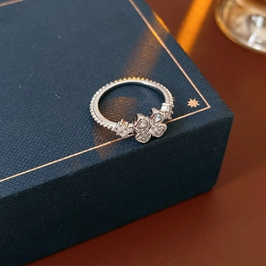 Macro view of silver clover ring with zircon stones on a navy leather jewelry box