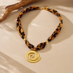 Detailed shot of leopard print ribbon necklace with a golden spiral relief pendant