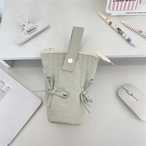Detailed top view of light green macaron pencil case with bow accents and handle on desk