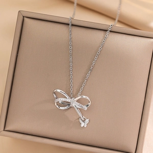 Irregular silver bow necklace with crystal pendant and beads in a beige jewelry box