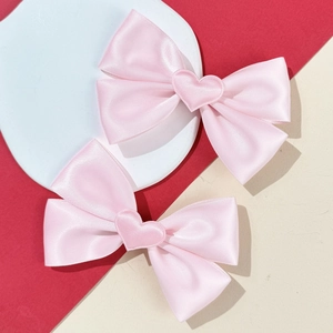 Détail de nœuds à cheveux en satin rose avec cœurs sur support en pierre blanche