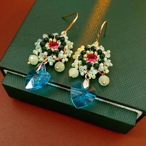 Dettaglio di orecchini vintage a fiore e cuore con cristallo blu e perle intrecciate