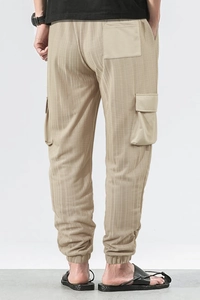Detail showing breathable checkered fabric texture and large cargo side pockets on beige pants