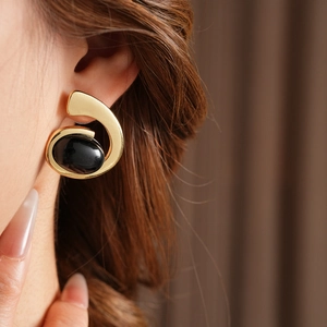 Close-up of vintage geometric gold earring with oval black stone on a model