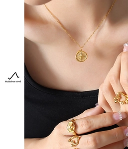 Detail of compass pendant and stainless steel gold rings on model wearing black clothes