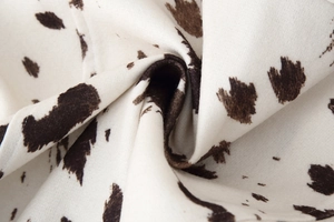 Detail shot of soft cow print flannel fabric with white and brown spotted texture