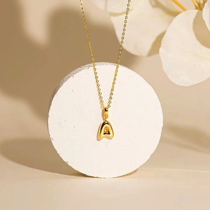 Golden bubble initial A pendant necklace with thin chain on minimalist stone stand