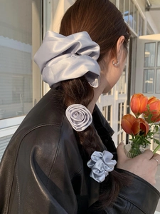 Three-piece silver gray silk hair accessory set styled on a woman's hair in a cozy room