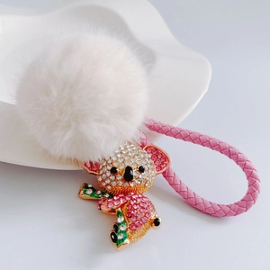 Detail of koala keychain with white fur pompom and pink braided leather cord on a tray