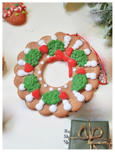 Macro detail of gingerbread man Christmas wreath ornament with red ribbon on book page
