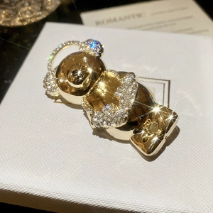 Close-up of golden bear brooch with sparkling crystals on textured white jewelry box