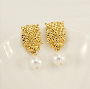 Close-up of gold woven texture earrings with dangling white pearl drop detail