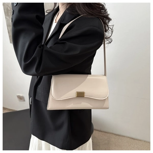 Close-up of minimalist cream flap shoulder bag with elegant gold vertical metal buckle