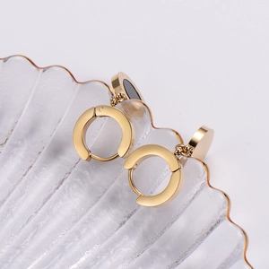 Golden earrings with Roman numerals and black inlay on a textured glass tray