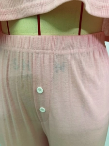 Detail of light pink knit pajama pants with hollow jacquard texture and decorative buttons